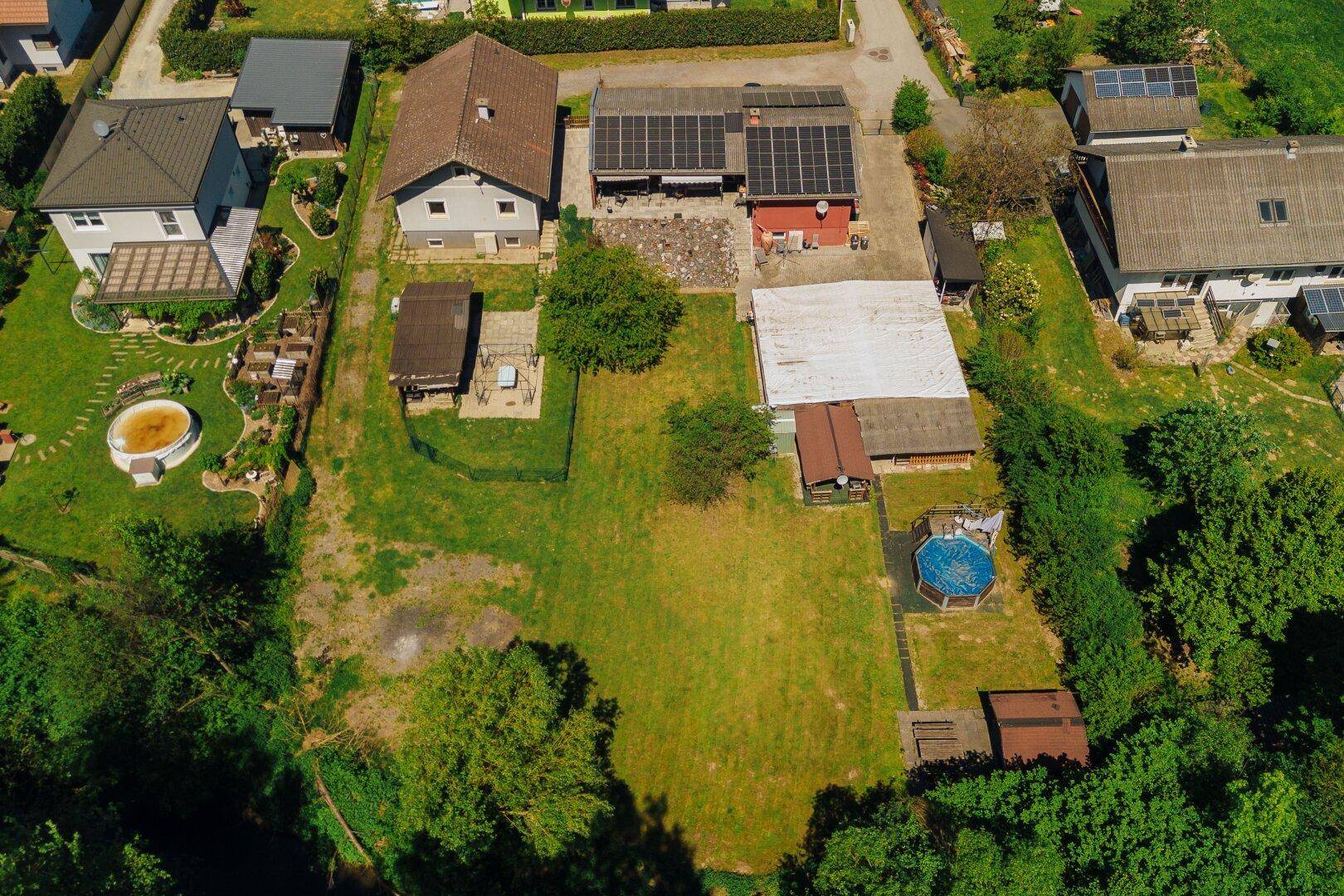 Übersicht des Anwesens von oben mit großzügiger Grünfläche, Pool und Solaranlagen auf dem Dach.