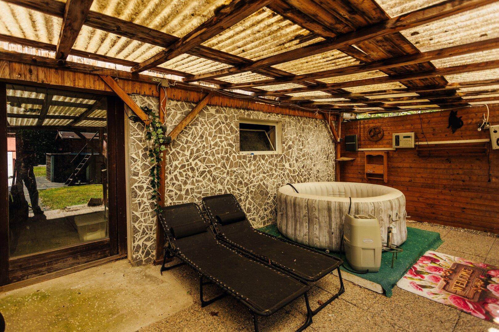 Überdachter Außenbereich mit Whirlpool, Liegestühlen und dekorativen Mosaikwänden.
