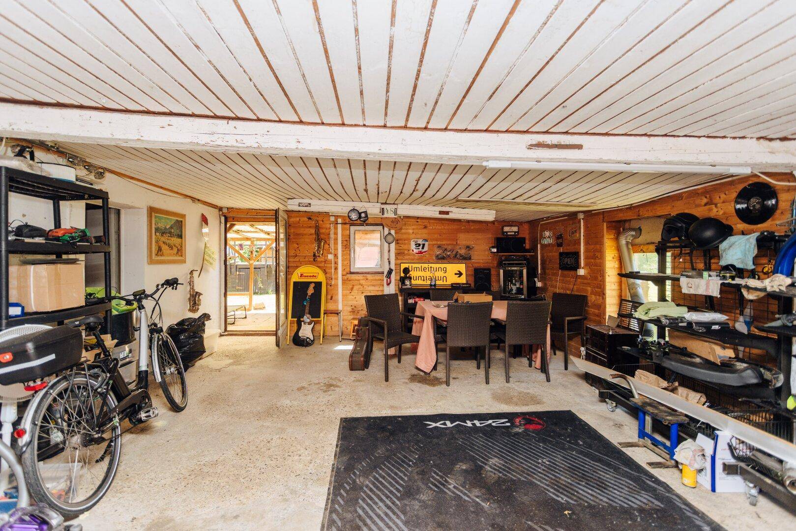 Rustikaler Raum mit Holzverkleidung, Esstisch, Fahrrädern und Regalen für Lagerung.