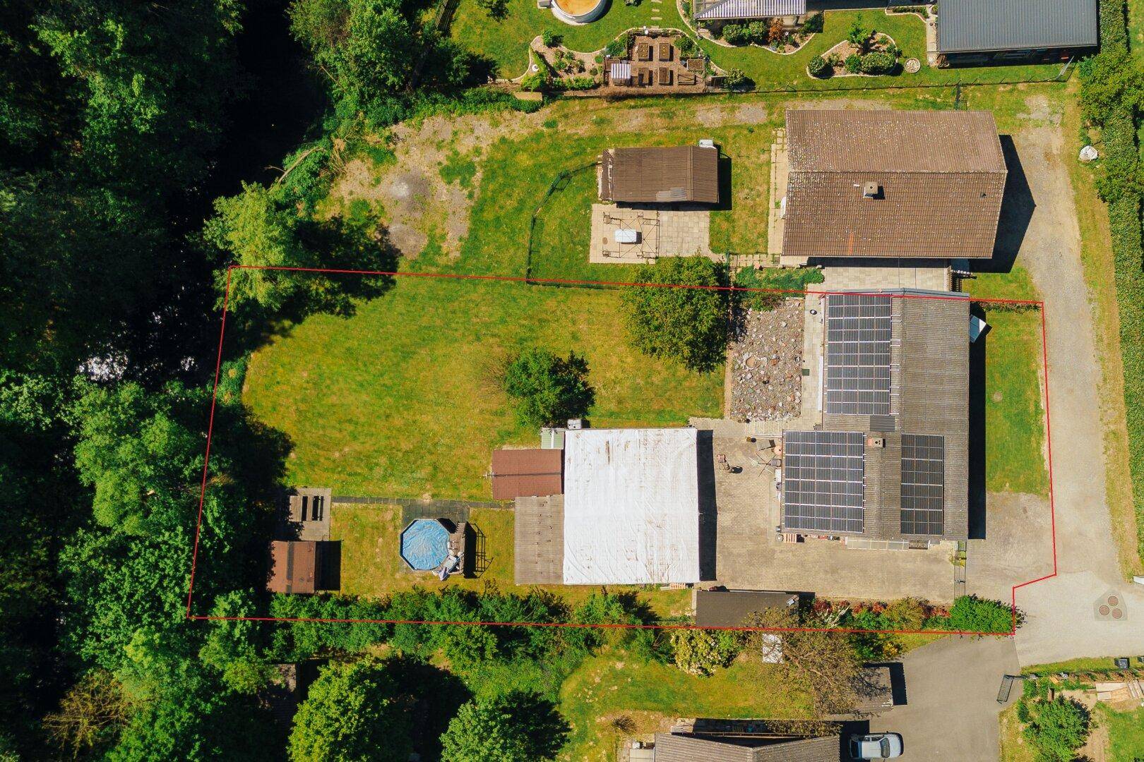 Luftaufnahme des Anwesens mit großem Garten, Pool und Solaranlage auf dem Dach.