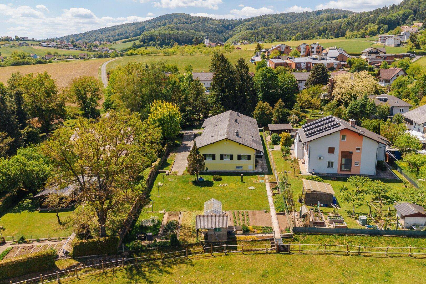 Übersicht des Anwesens mit großem Garten, Gewächshaus und angrenzenden Feldern.