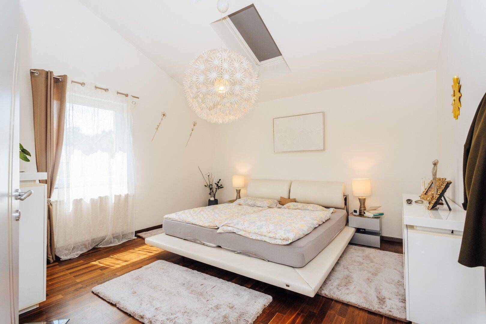 Geräumiges Schlafzimmer mit Doppelbett, Holzboden und Dachschräge.