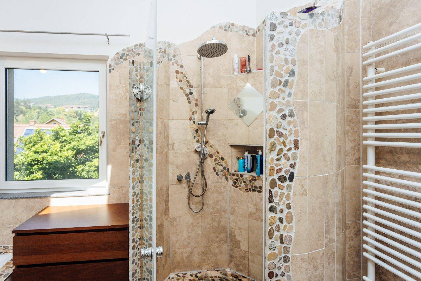 Modernes Badezimmer mit begehbarer Dusche, Natursteinfliesen und Fenster mit Ausblick.