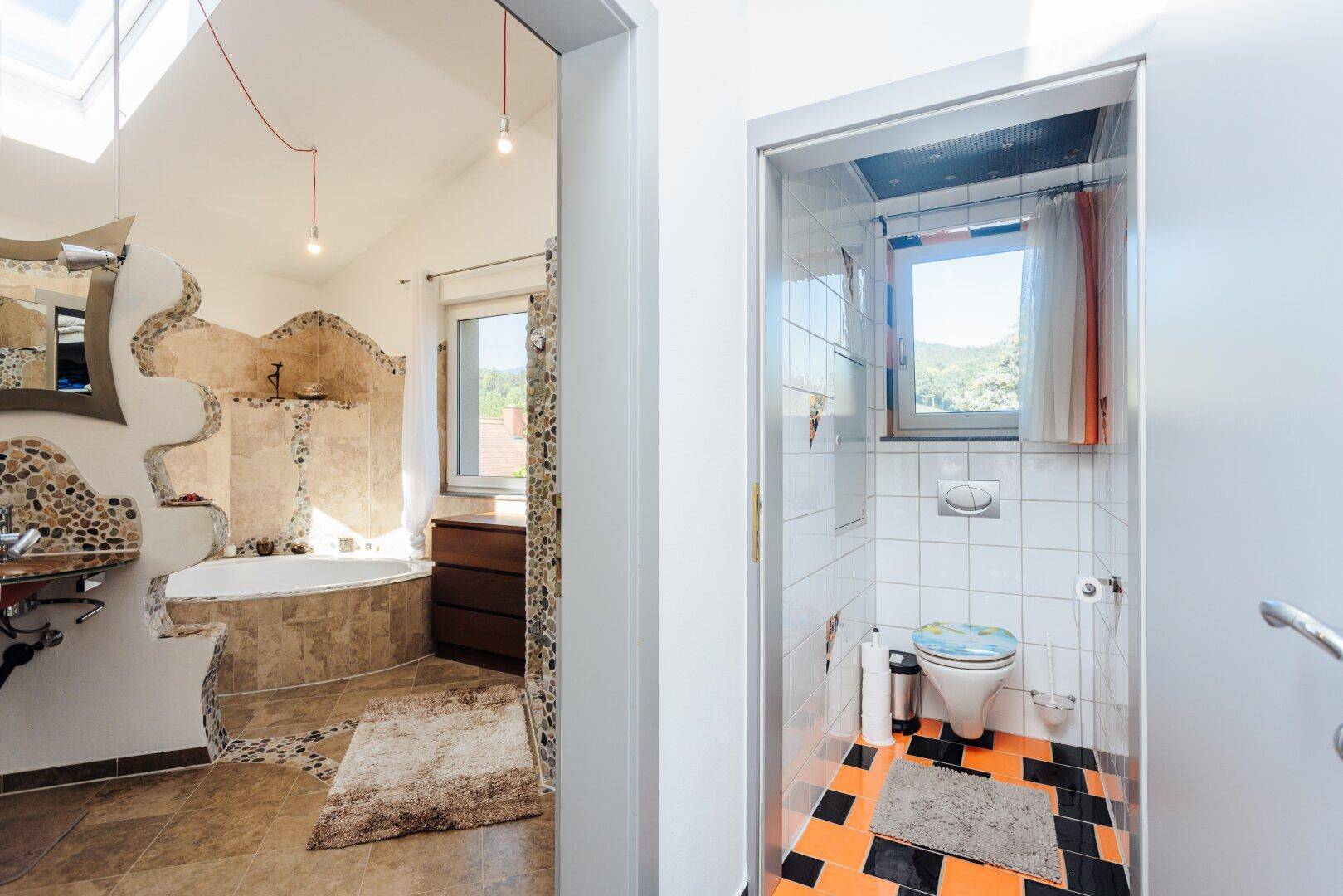 Geräumiges Badezimmer mit Badewanne und separatem Gäste-WC mit farbigen Fliesen.
