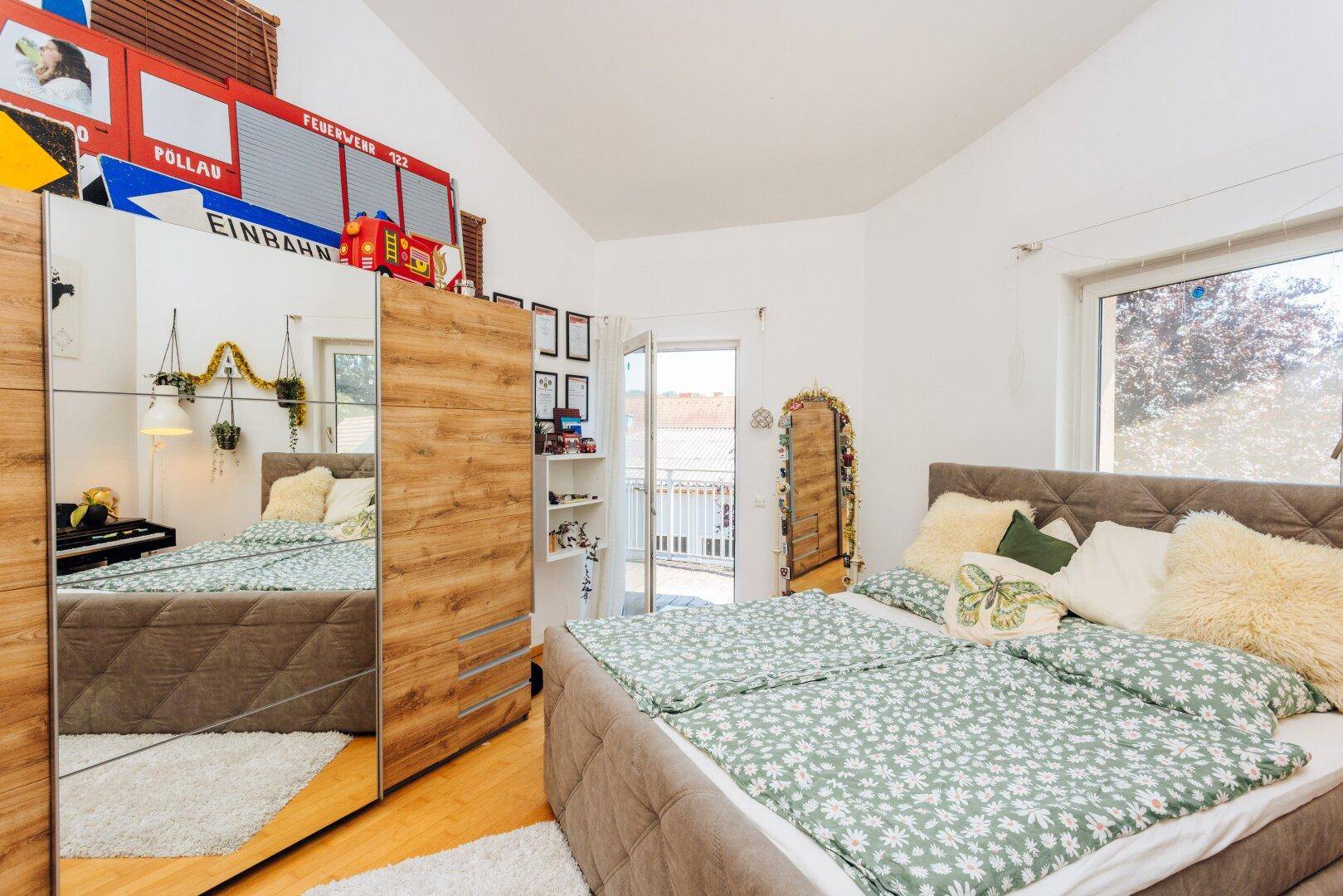 Helles Schlafzimmer mit Holzboden, großem Kleiderschrank und Zugang zum Balkon.