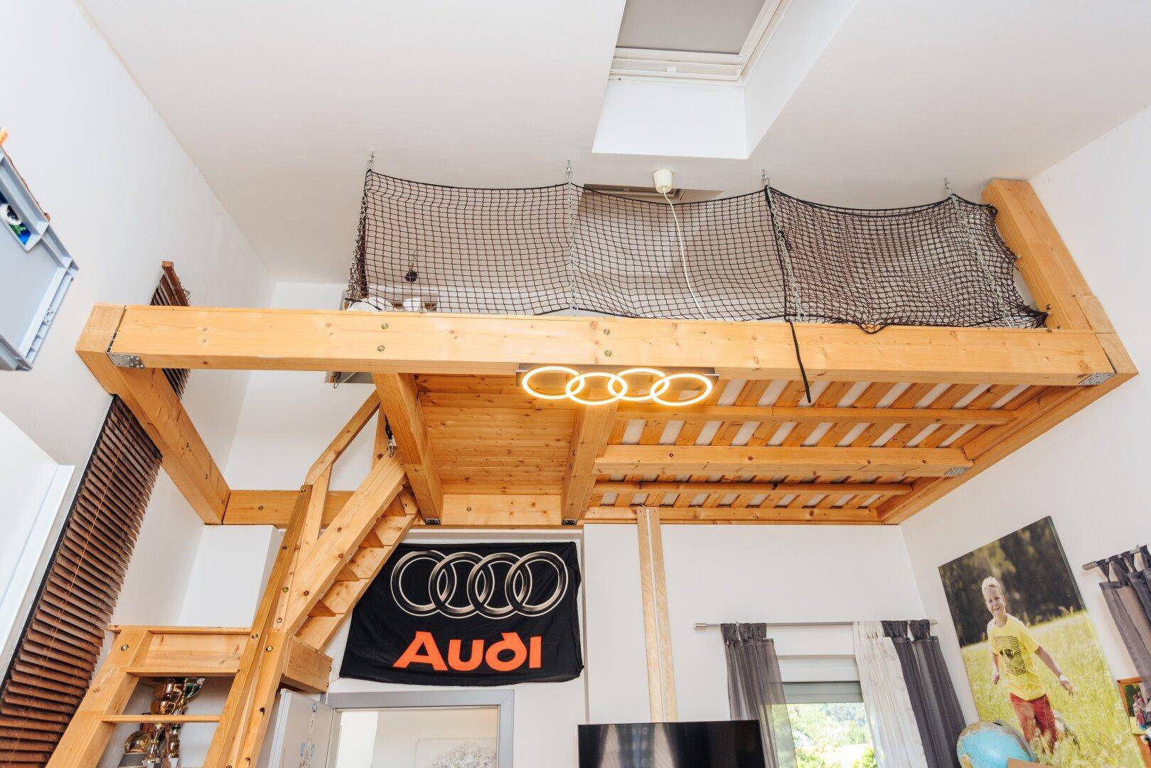 Hochbettkonstruktion aus Holz mit Sicherheitsnetz und Oberlicht für natürliches Licht.