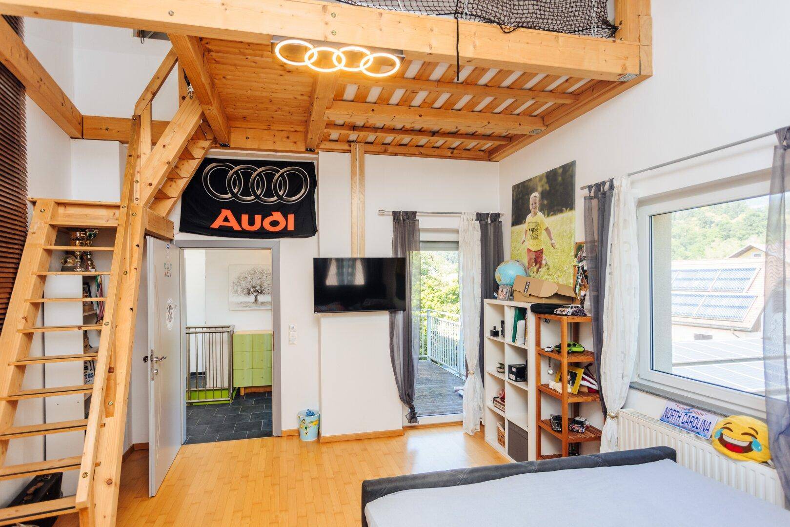 Kinderzimmer mit Hochbett, Holzboden und Zugang zum Balkon mit Blick ins Grüne.