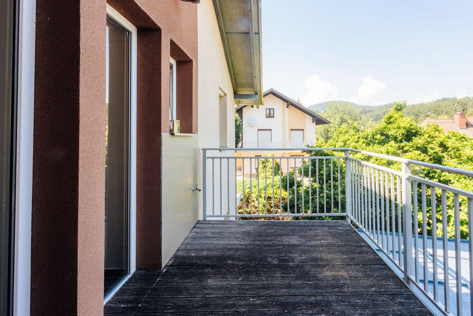 Balkon mit Holzboden und Metallgeländer bietet Blick auf die Nachbarschaft und Hügel.