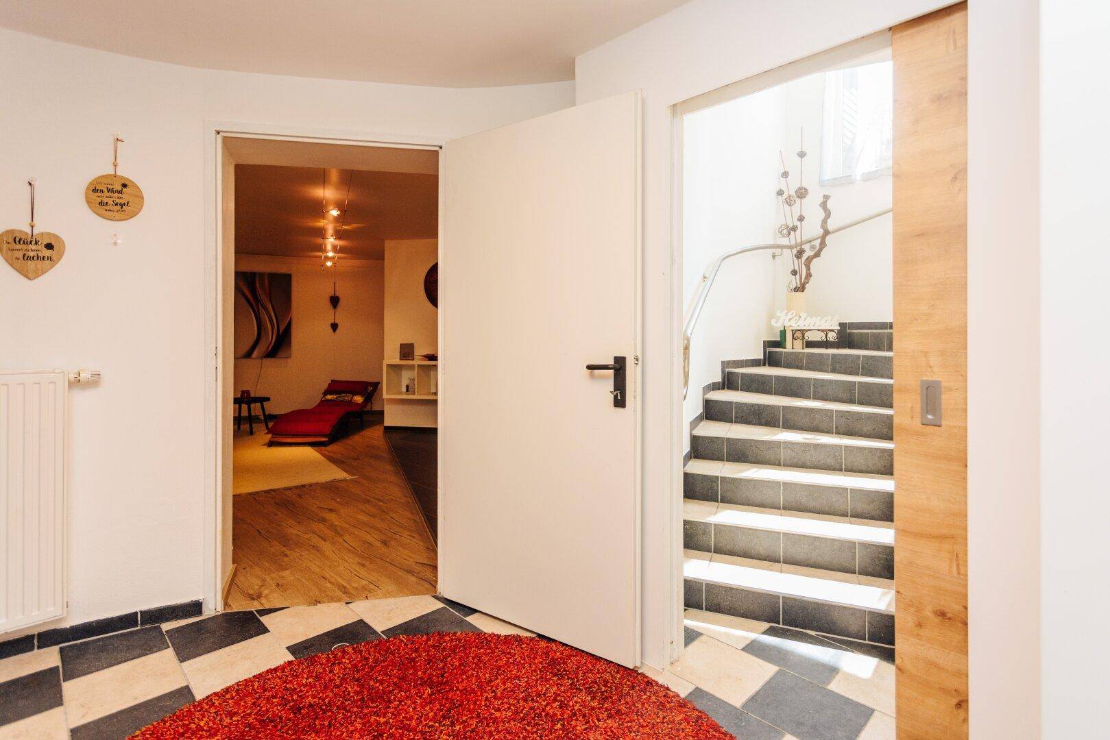 Eingangsbereich mit Fliesenboden und Zugang zu einem Wellnessbereich und Treppenhaus.
