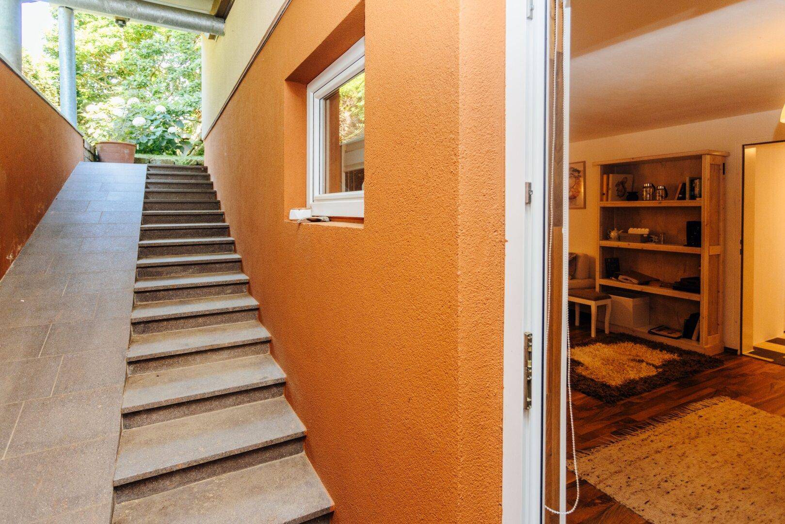 Außentreppe führt zum Eingangsbereich des Hauses mit orangefarbener Fassade.