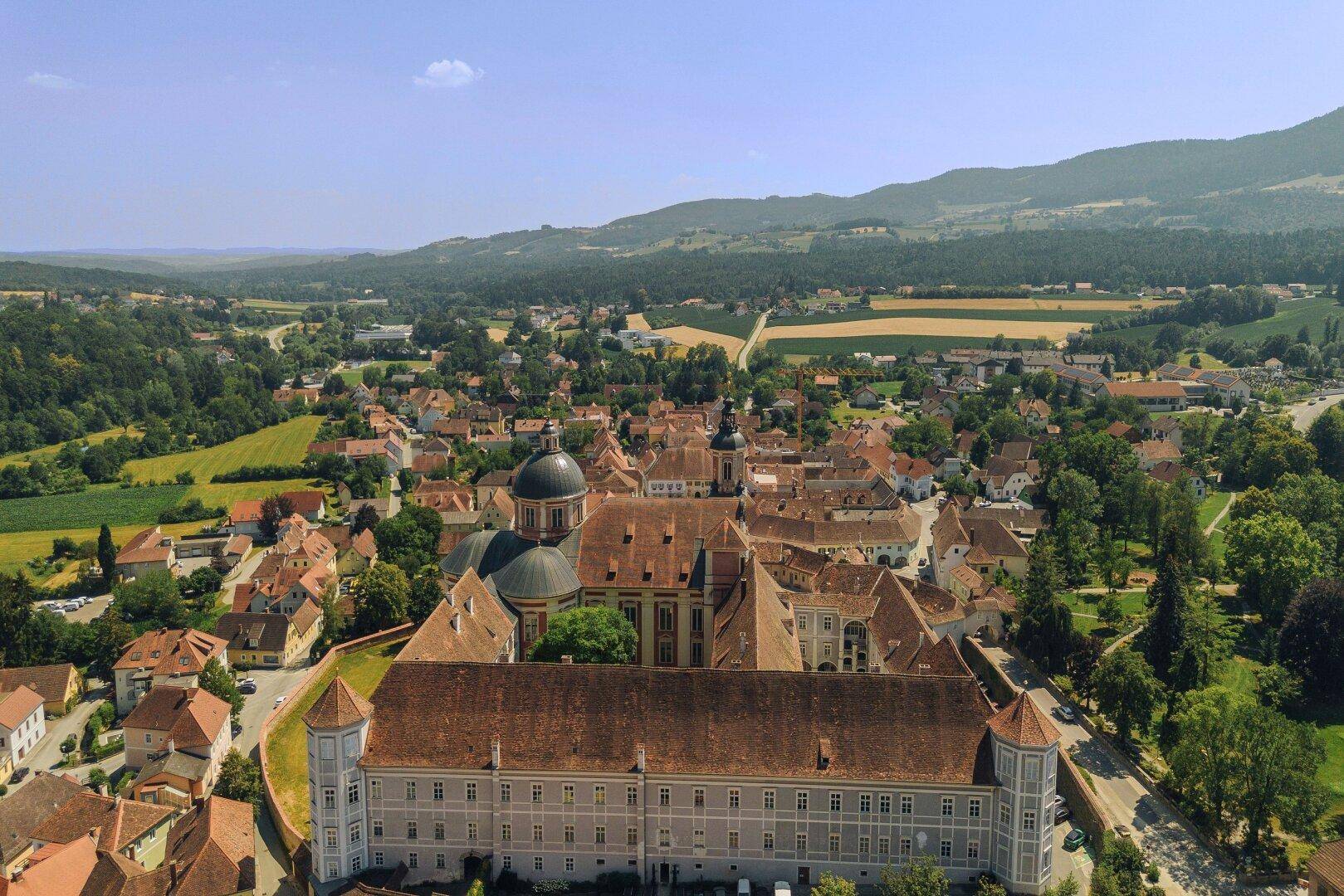 Panoramablick auf ein imposantes historisches Gebäude und die umliegende ländliche Dorflandschaft.