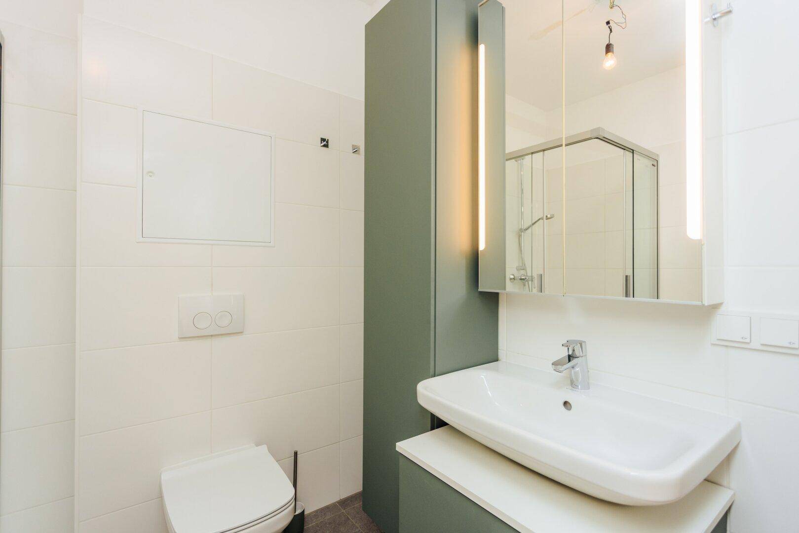 Modernes Badezimmer mit Einzelwaschbecken, Spiegelschrank mit Beleuchtung und wandhängendem WC.