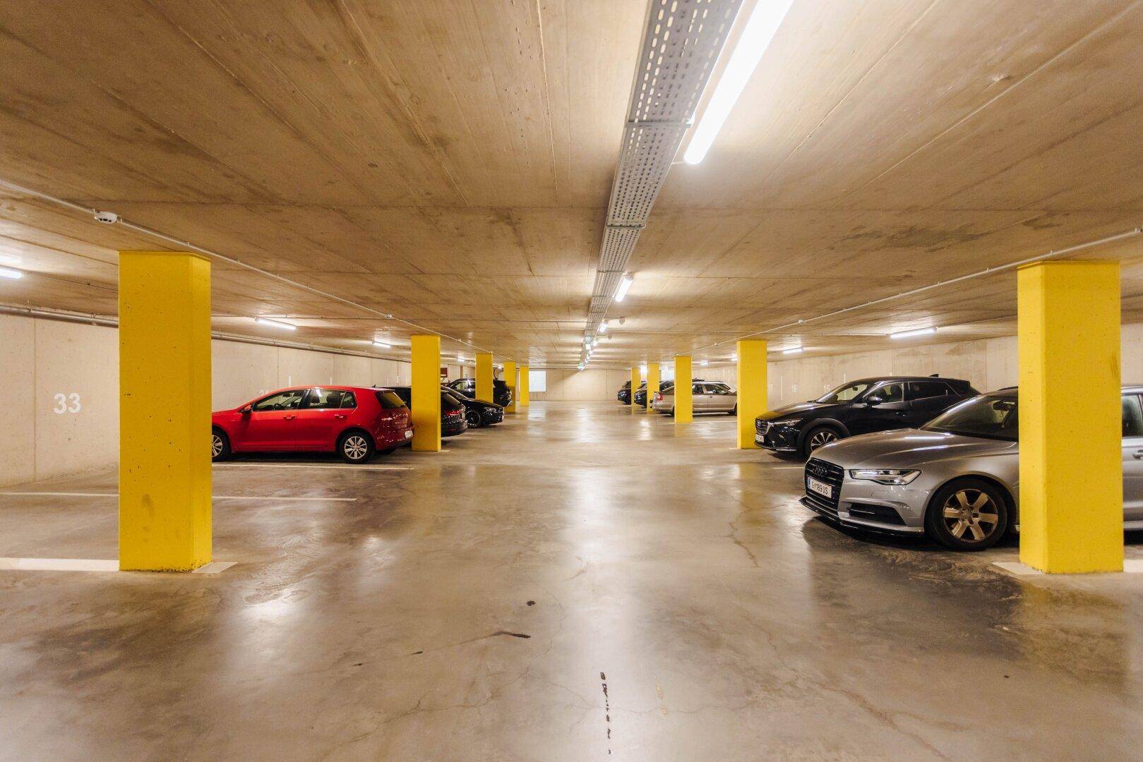 Tiefgarage mit geparkten Autos und markanten gelben Säulen, bietet sichere Stellplätze.