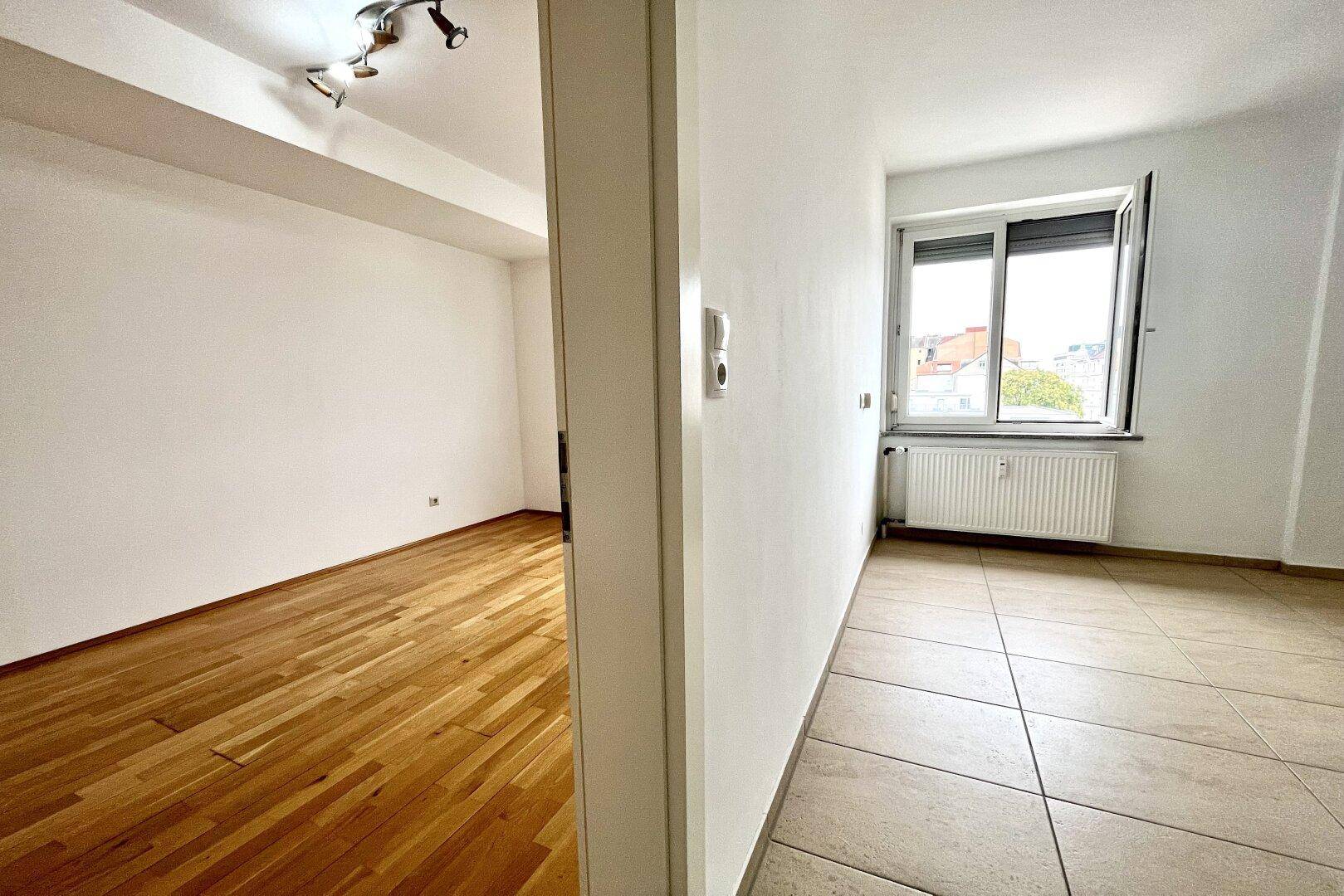 Übergangsbereich zwischen zwei Räumen mit Fliesen- und Parkettboden.