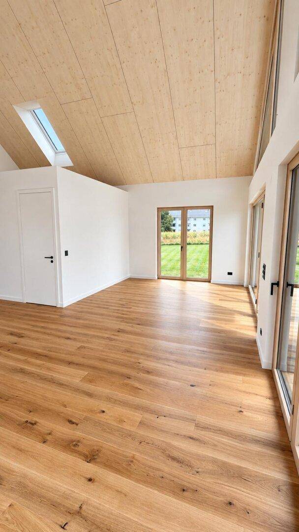 Geräumiger, heller Raum mit Holzboden, Dachfenster und Zugang zum Garten.