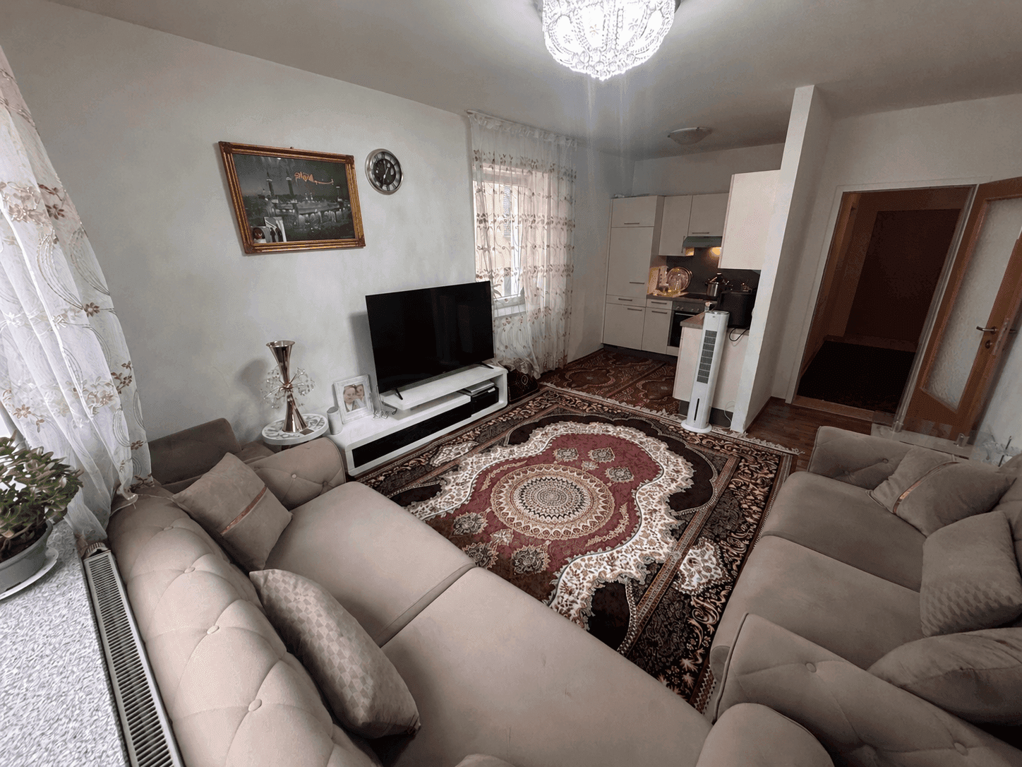 Offener Wohnbereich mit bequemen Sofas, Fernseher und einer integrierten kleinen Küchenzeile im Hintergrund.