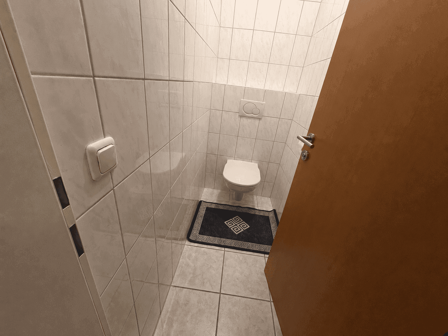Separates WC mit wandhängender Toilette und Fliesenboden in einem gepflegten Zustand.