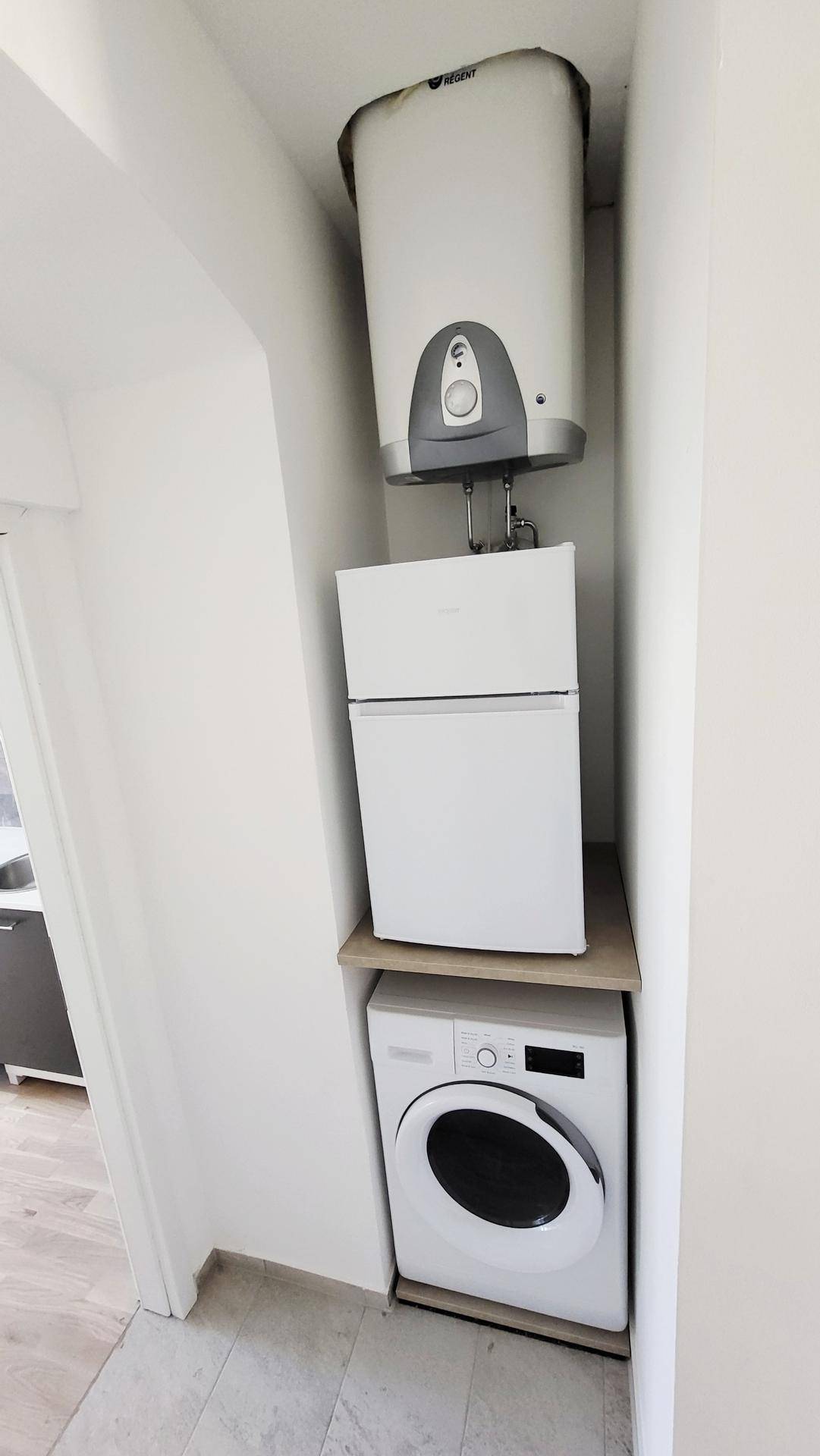 Praktischer Hauswirtschaftsbereich mit Waschmaschine, Kühlschrank und Warmwasserboiler.