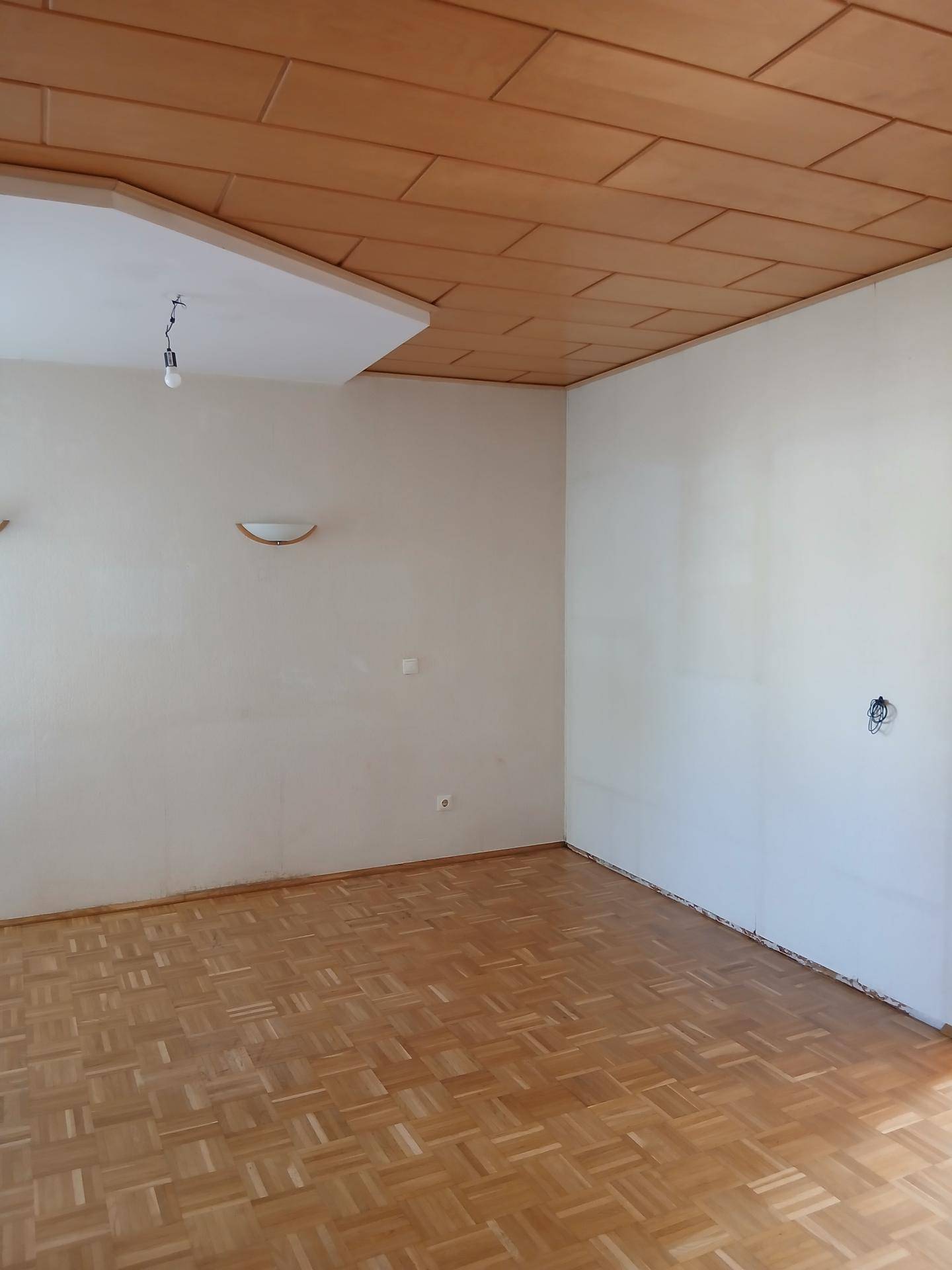 Heller Raum mit Parkettboden und Holzdecke, bereit zur individuellen Gestaltung.