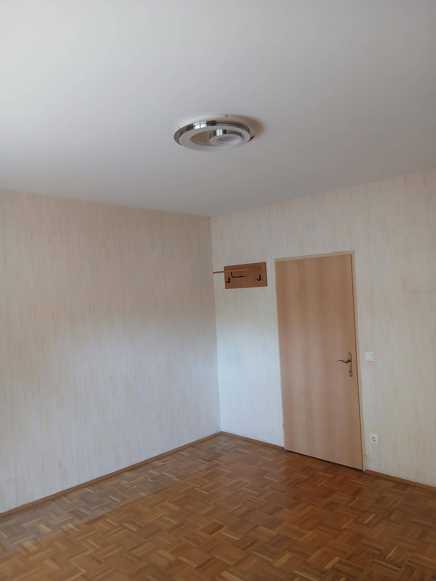 Geräumiges Schlafzimmer mit Parkettboden und Holztür, ideal für individuelle Gestaltung.