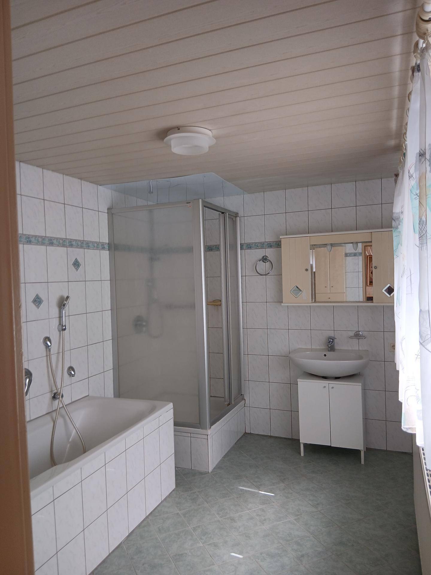 Badezimmer mit Badewanne, Duschkabine, Waschbecken und hellen Fliesen.