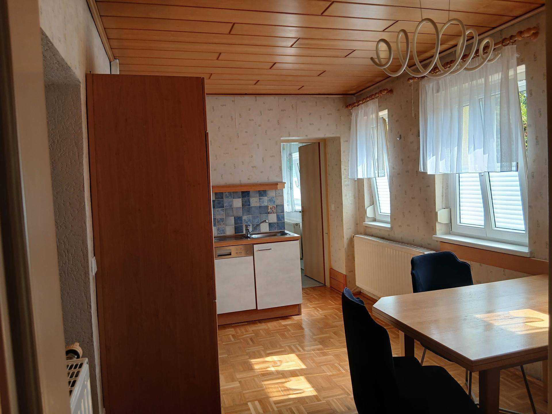 Gemütliche Wohnküche mit Essbereich, Holzdecke und kleiner Küchenzeile.