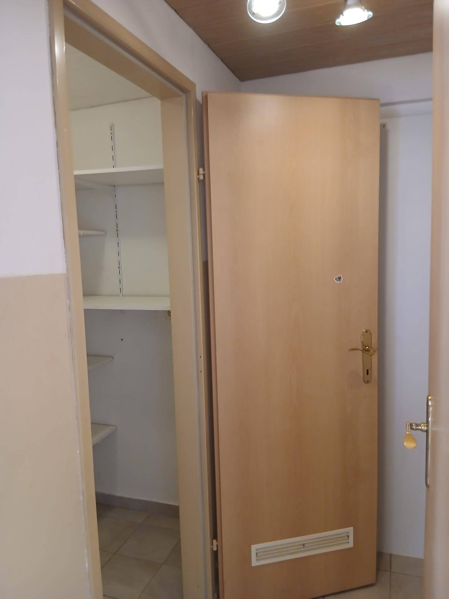 Flur mit offener Tür zur Speisekammer und Eingangstür.