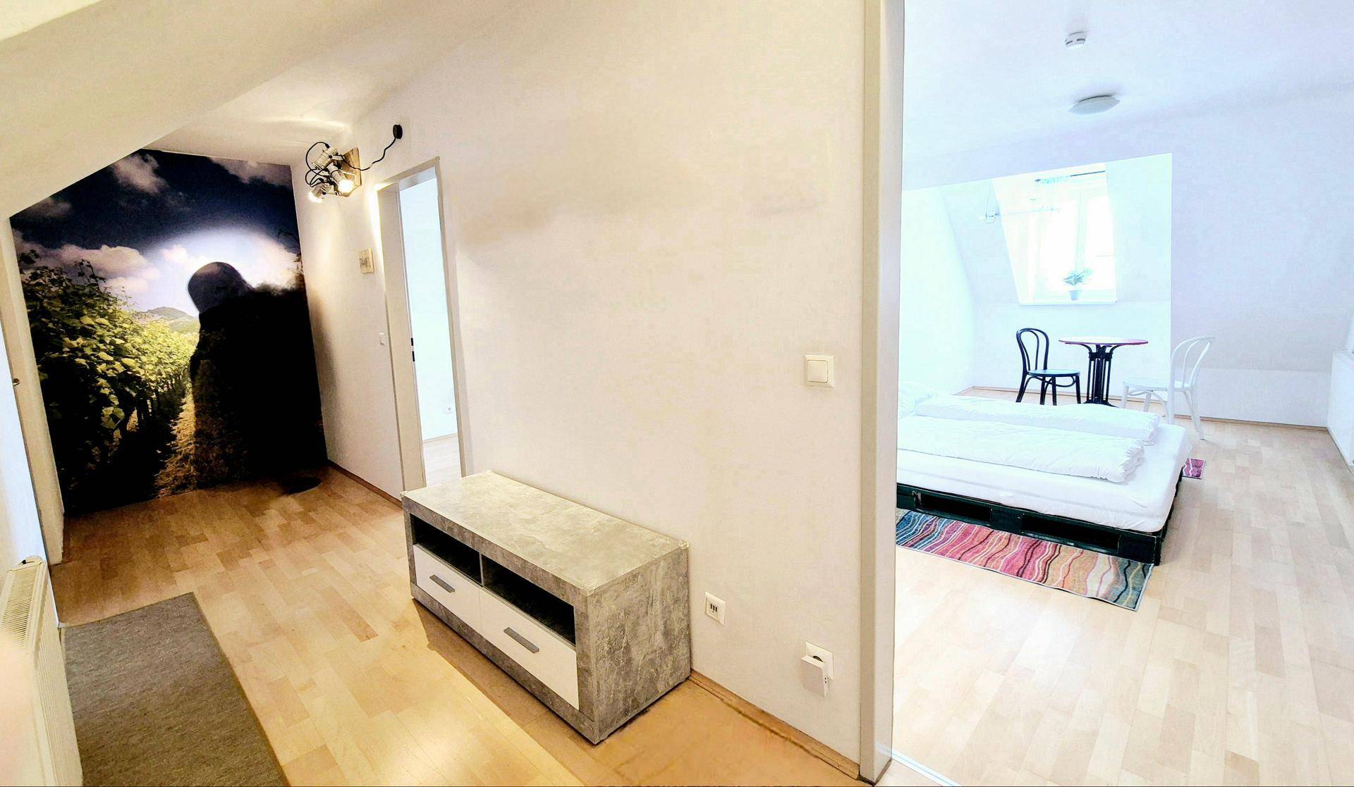Flur mit Holzboden und Zugang zu einem Schlafzimmer mit Dachschräge.