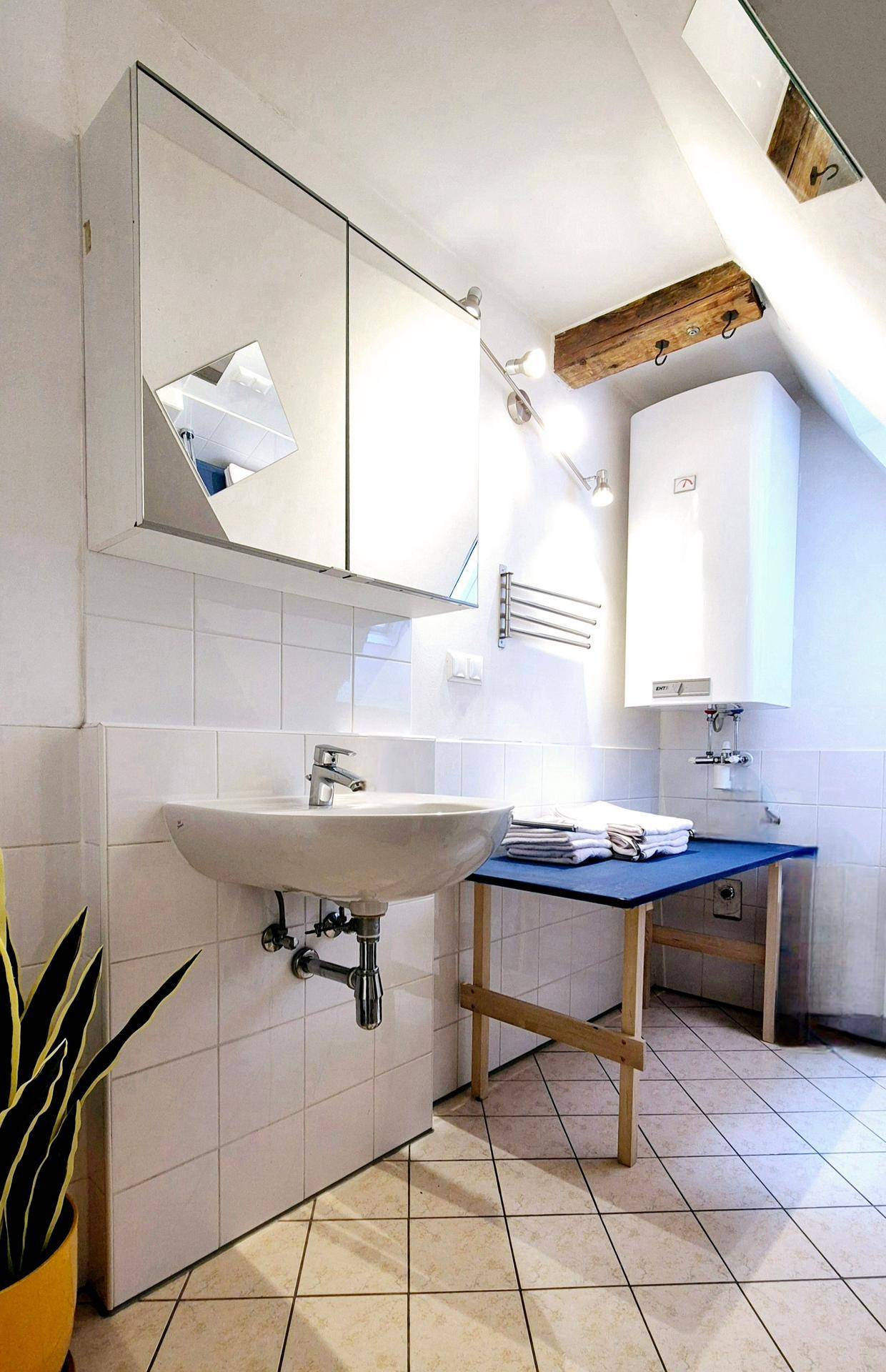 Badezimmer mit Fliesenboden, Waschbecken, Spiegelschrank und Dachschräge.