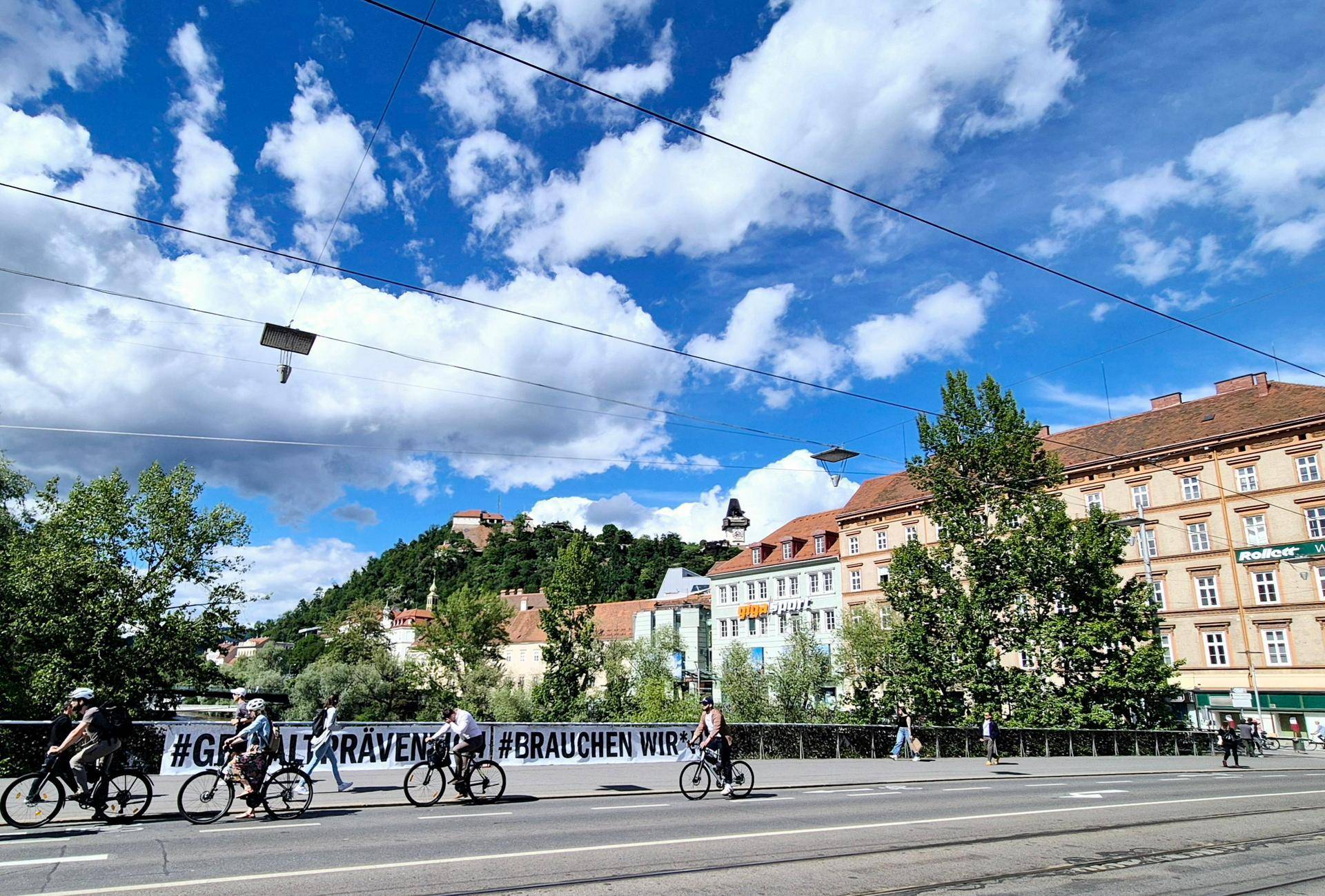 Brückenansicht mit Radfahrern, Fluss und der historischen Stadtkulisse im Hintergrund.
