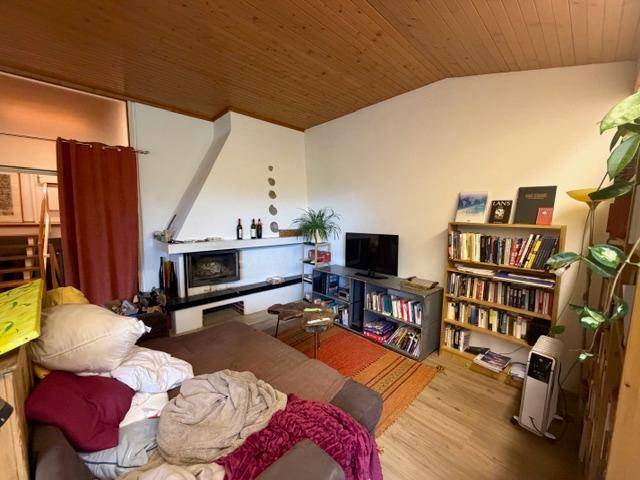 Gemütliches Wohnzimmer mit Holzbalkendecke, Kamin und Bücherregal.