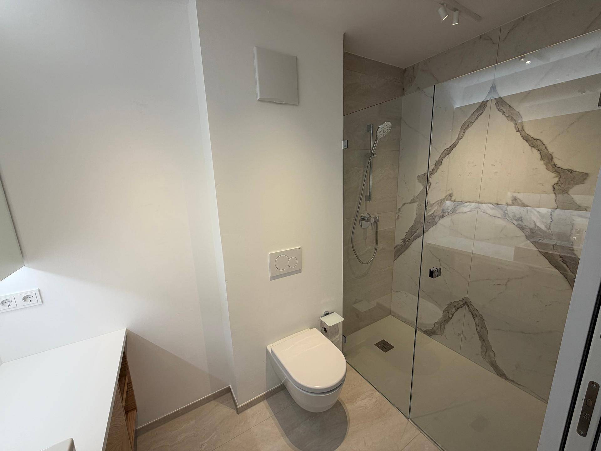 Modernes Badezimmer mit begehbarer Dusche, Wand-WC und eleganten Marmorfliesen.