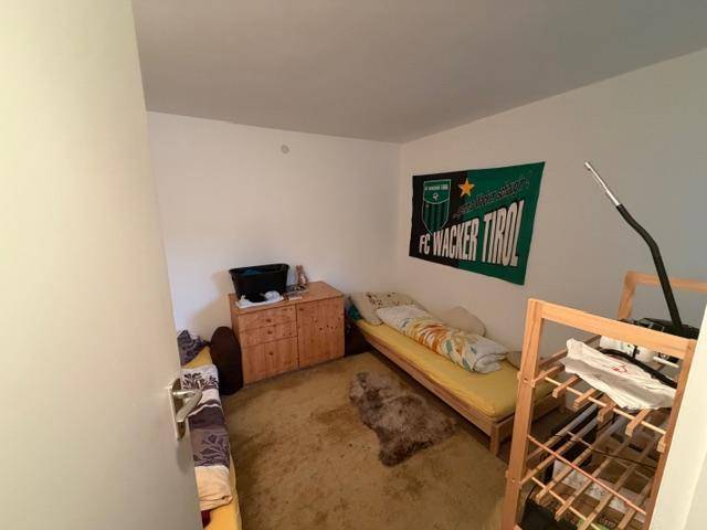 Kleines Schlafzimmer oder Gästezimmer mit Teppichboden und einfacher Einrichtung.