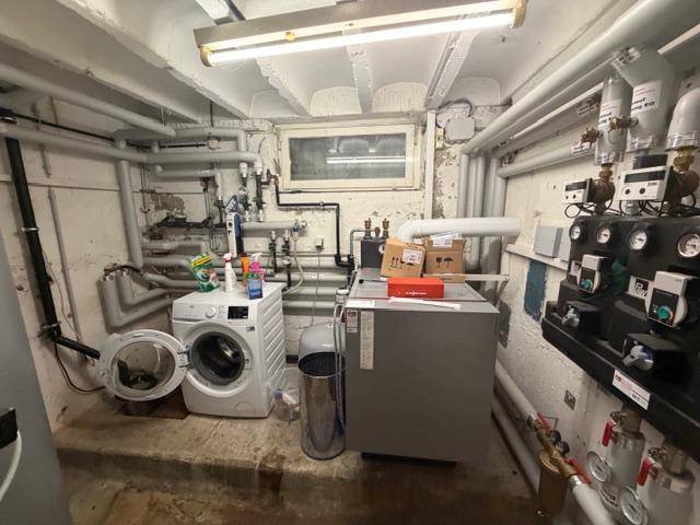 Funktionaler Hauswirtschaftsraum im Keller mit Waschmaschine und Heizungsanlage.