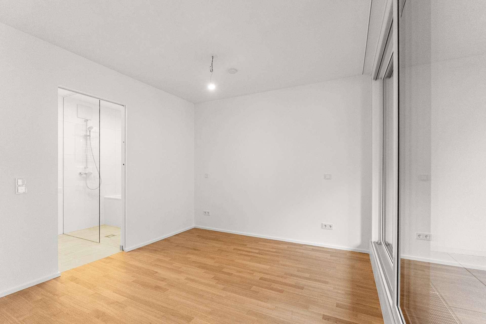 Helles Schlafzimmer mit Holzboden und direktem Zugang zu einem modernen Badezimmer.