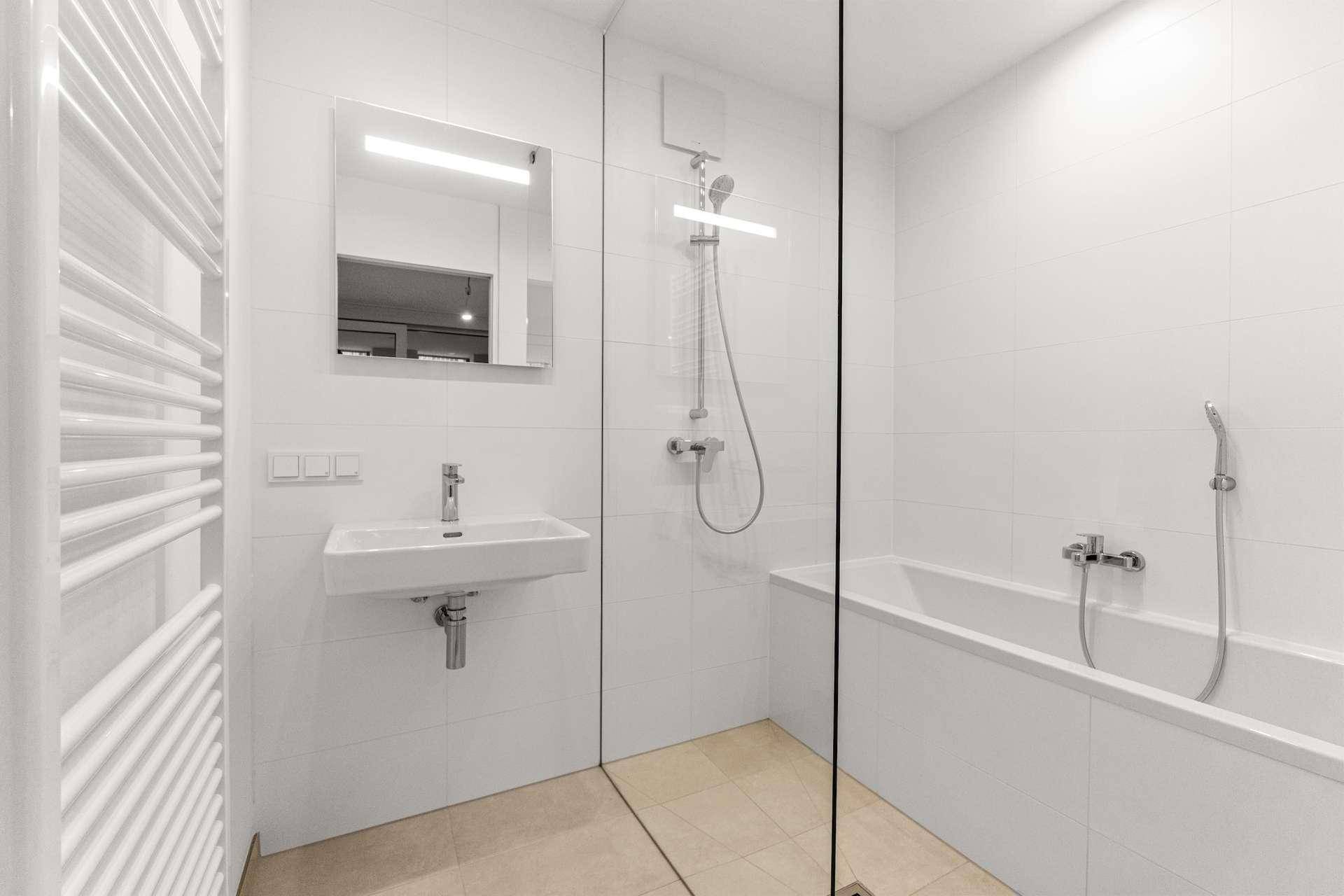 Modernes Badezimmer mit Badewanne, Duschbereich und beheiztem Handtuchhalter.