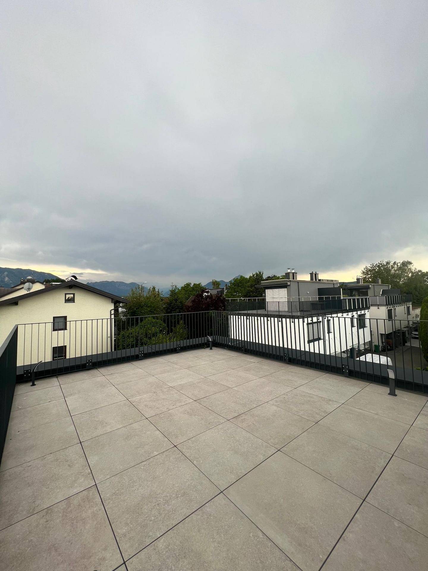 Weitläufige Dachterrasse mit Fliesenboden und Panoramablick auf die umliegende Landschaft und Berge.