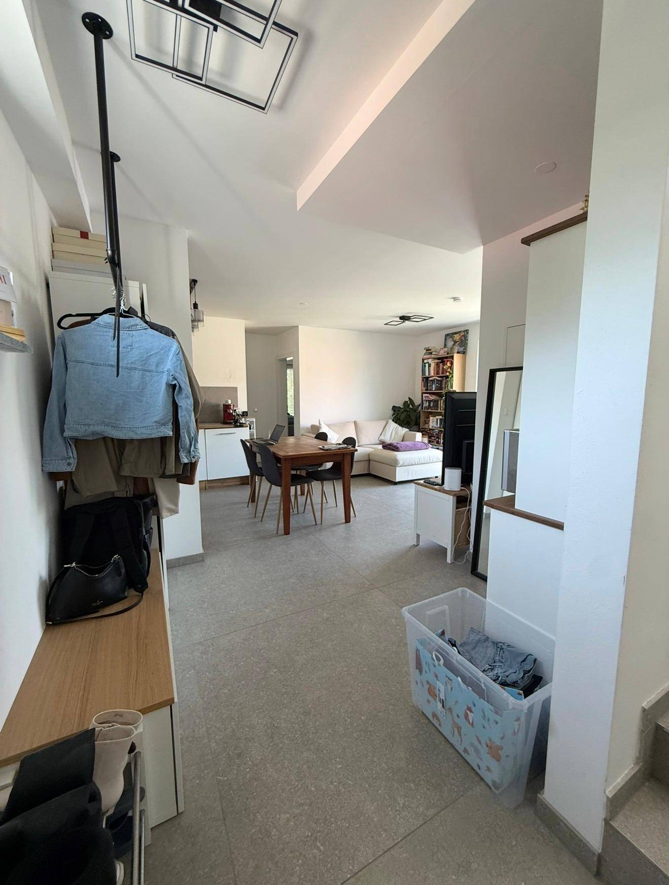 Heller Eingangsbereich mit Fliesenboden, Garderobe und Blick in den offenen Wohnbereich.