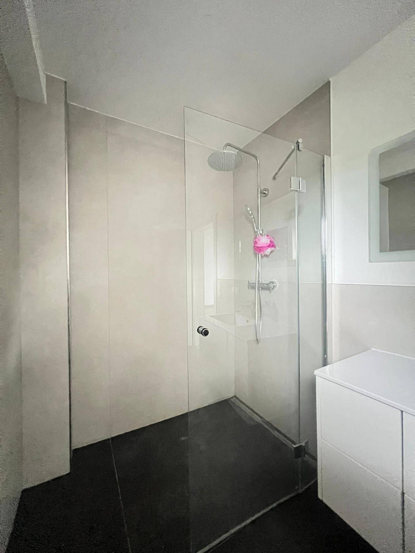 Geräumige Duschkabine mit Glaswand und moderner Armatur in hellem Badezimmer.
