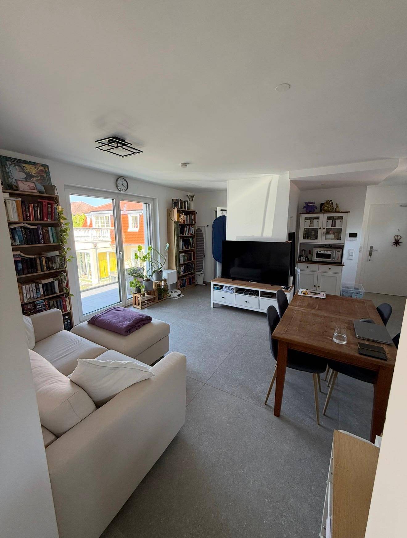 Gemütlicher Wohn- und Essbereich mit großem Sofa, Esstisch und Zugang zum Außenbereich.
