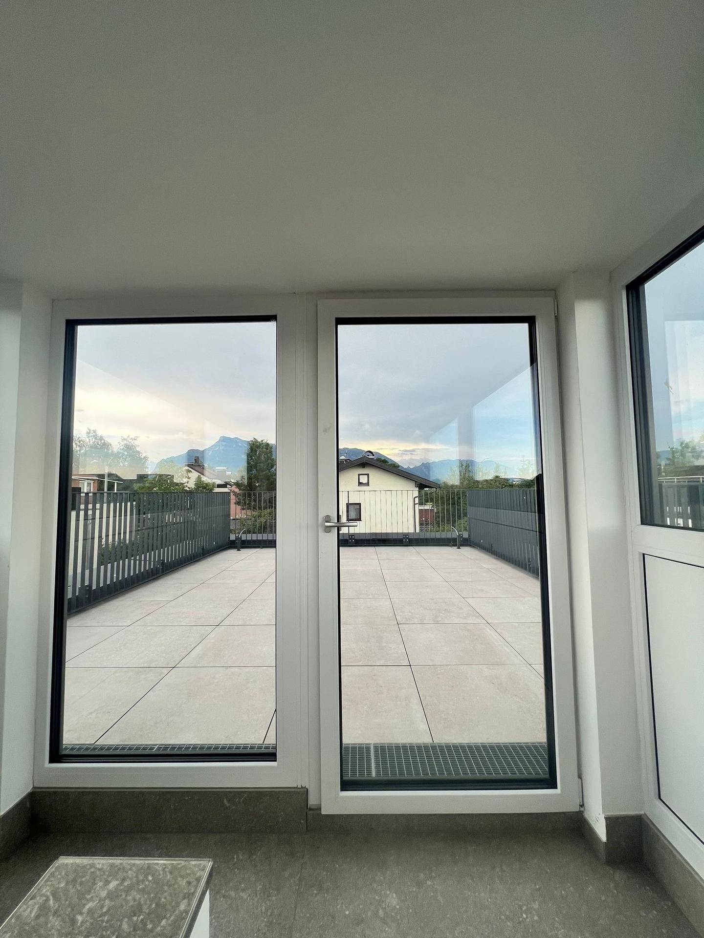 Geräumige Dachterrasse mit Fliesenboden und weitem Blick auf die Berge.