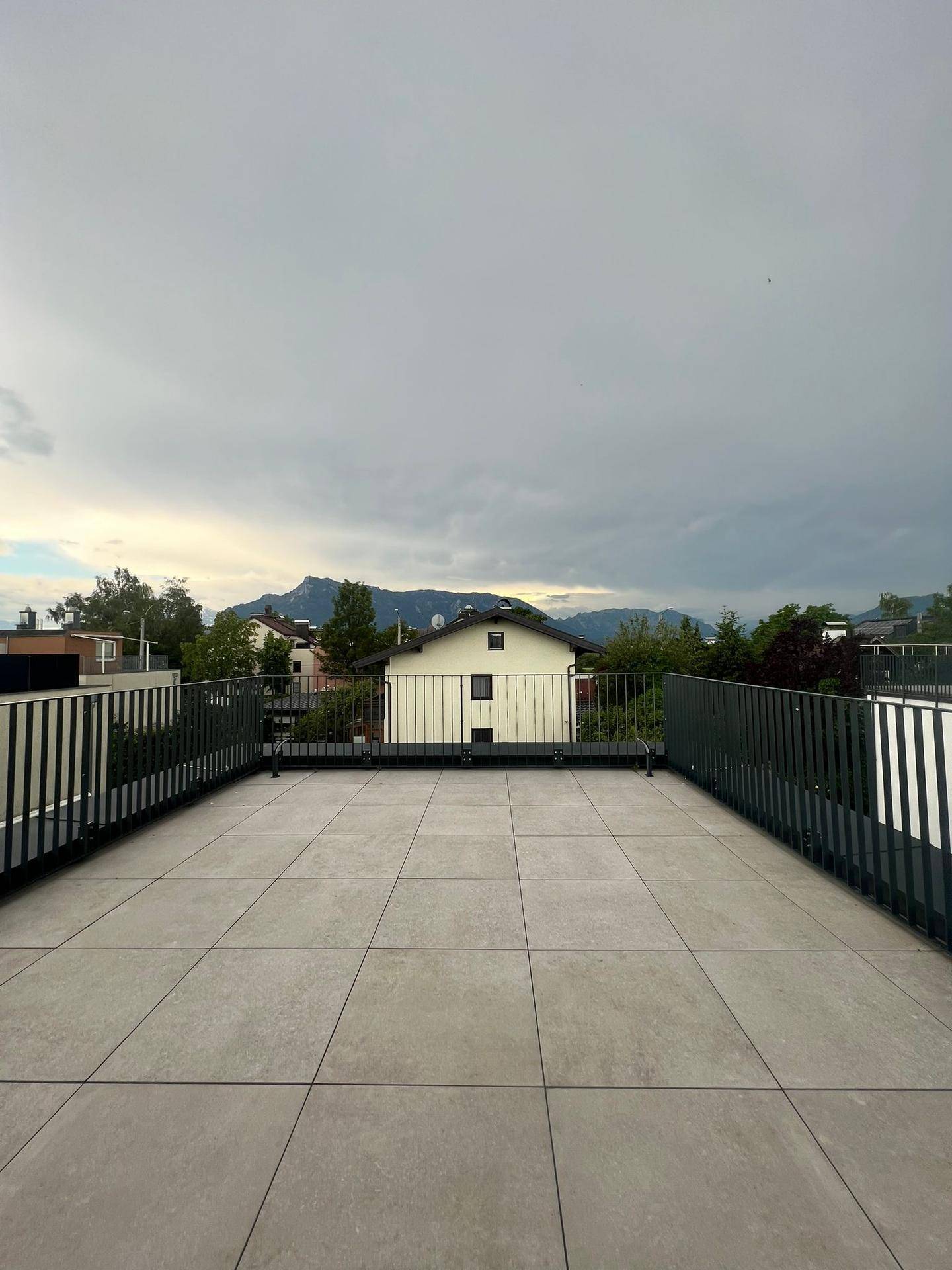 Weitläufige Dachterrasse mit Fliesenboden und Panoramablick auf die umliegende Landschaft und Berge.