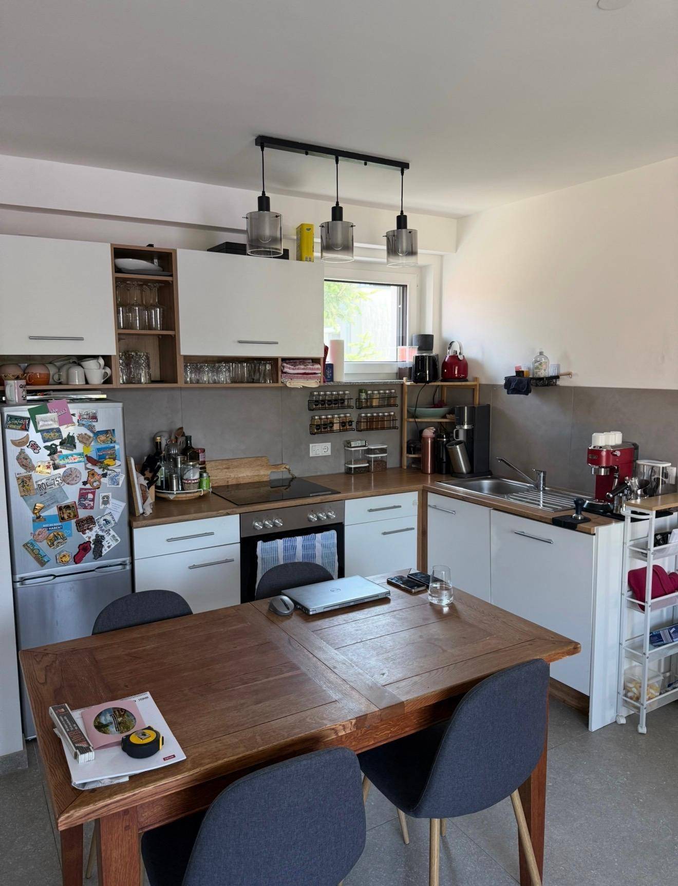 Moderne Einbauküche mit Holzarbeitsplatte, Essbereich und Fenster für Tageslicht.