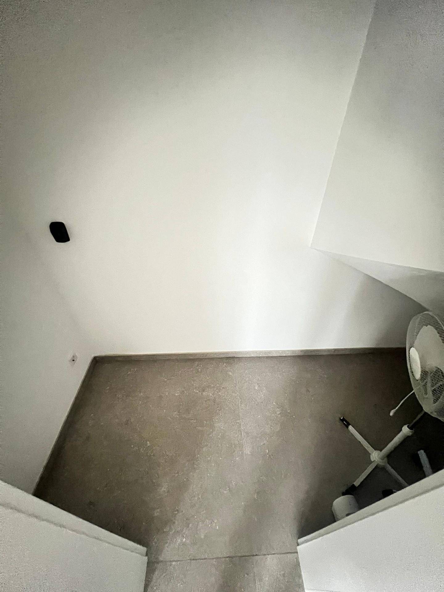 Kleiner Raum mit Fliesenboden und weiß gestrichenen Wänden.