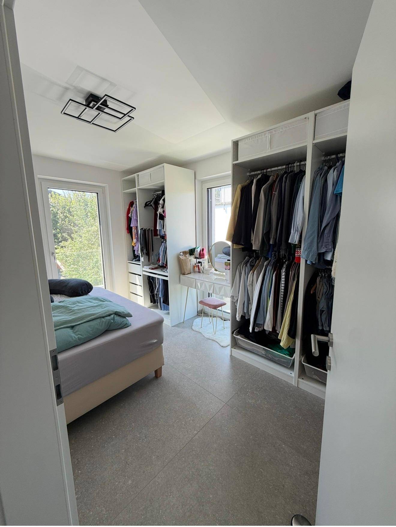 Helles Schlafzimmer mit großem Bett, Einbauschränken und viel Tageslicht.