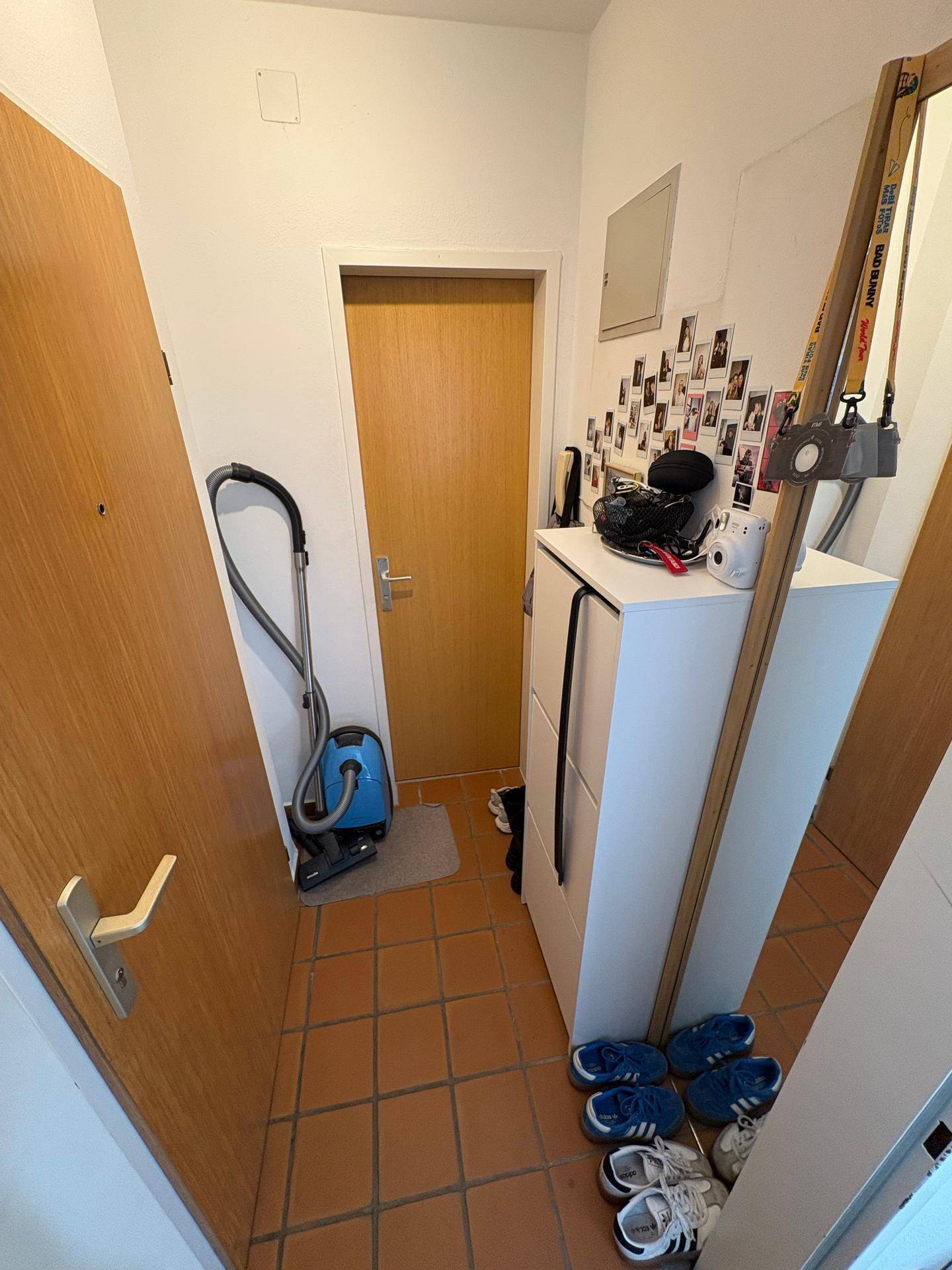 Eingangsbereich mit Terrakotta-Fliesenboden, Schuhschrank und einem großen Spiegel.