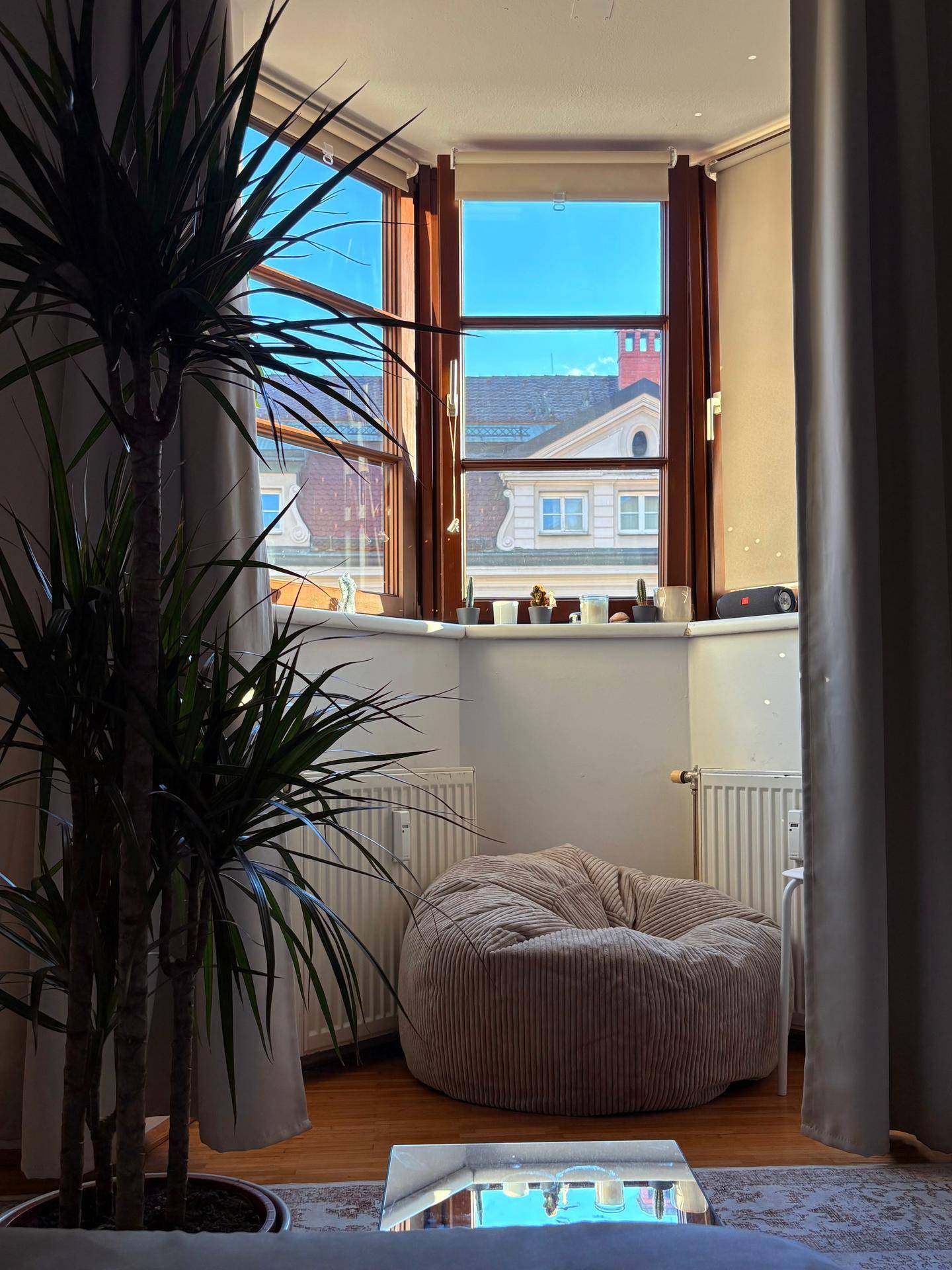 Gemütlicher Erkerbereich mit Sitzsack und großer Pflanze, bietet einen Blick auf die Dächer.