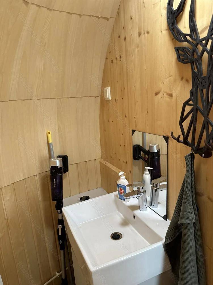Kleines Badezimmer mit modernem Waschbecken, Spiegel und Holzverkleidung an den Wänden.