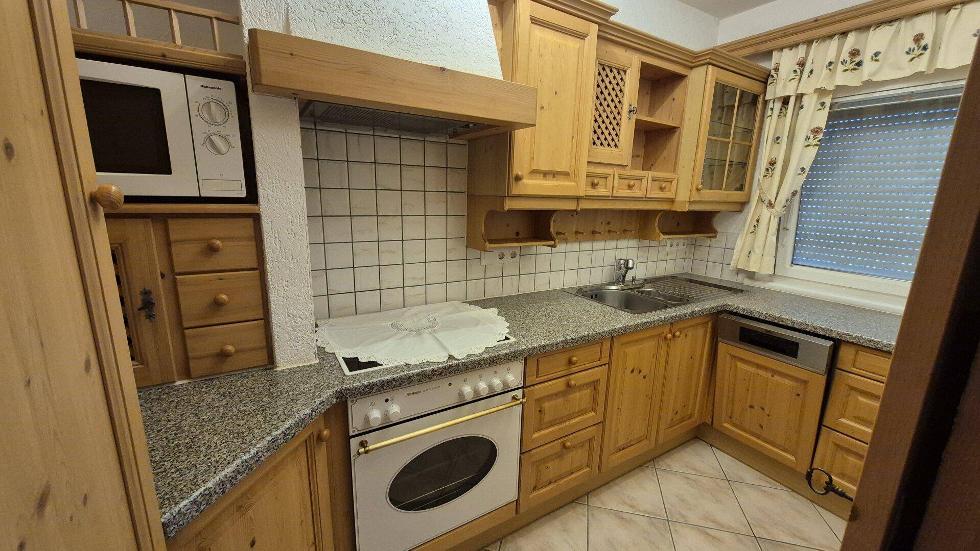 Traditionelle Holzküche mit Granitarbeitsplatten, integrierten Geräten und einem Fenster.
