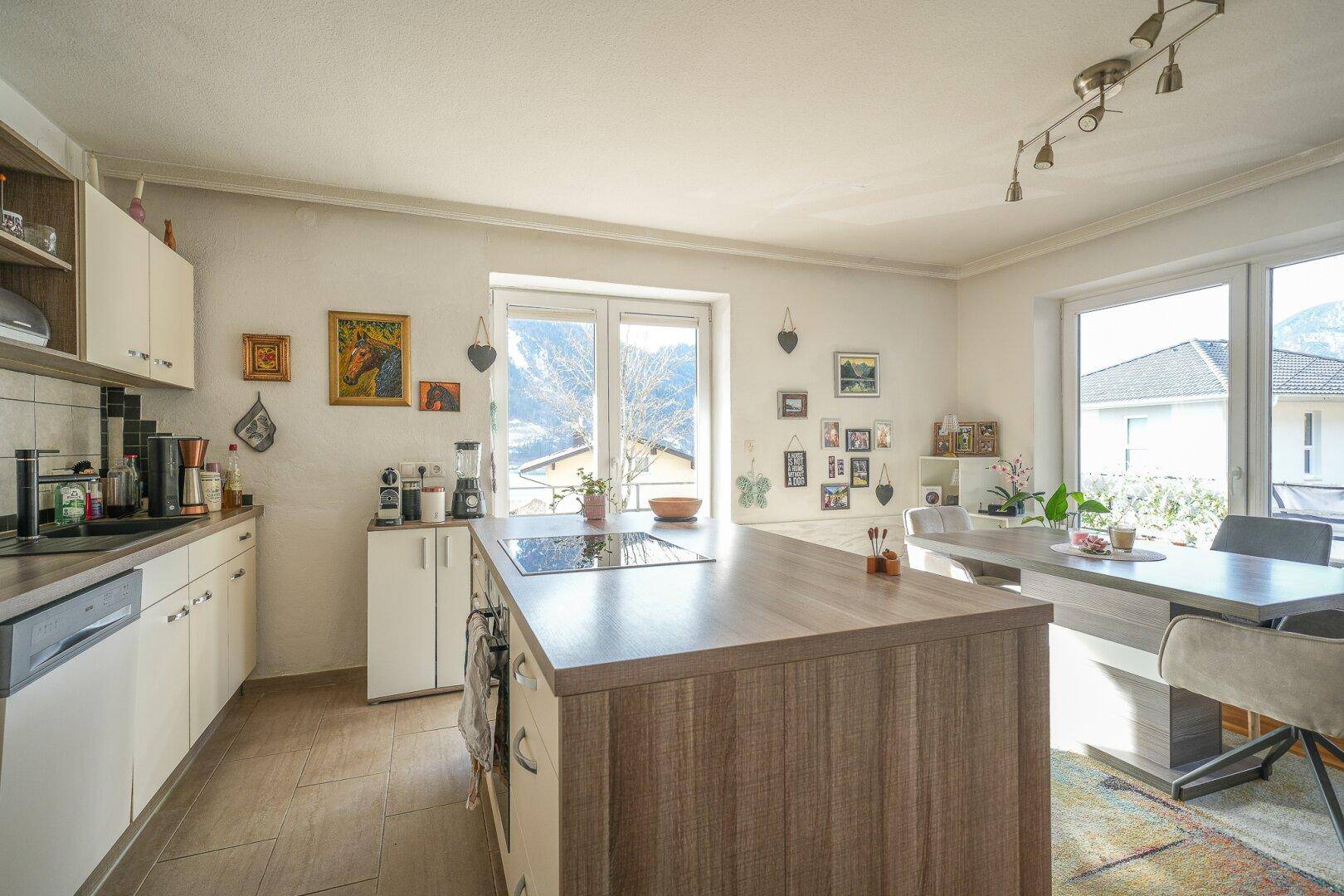 Helle Küche mit Kochinsel, Essbereich und Blick auf die Berge.
